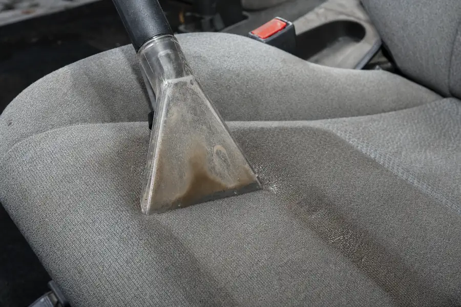 Extraction vacuum nozzle pulling dirty water out of a car seat cushion