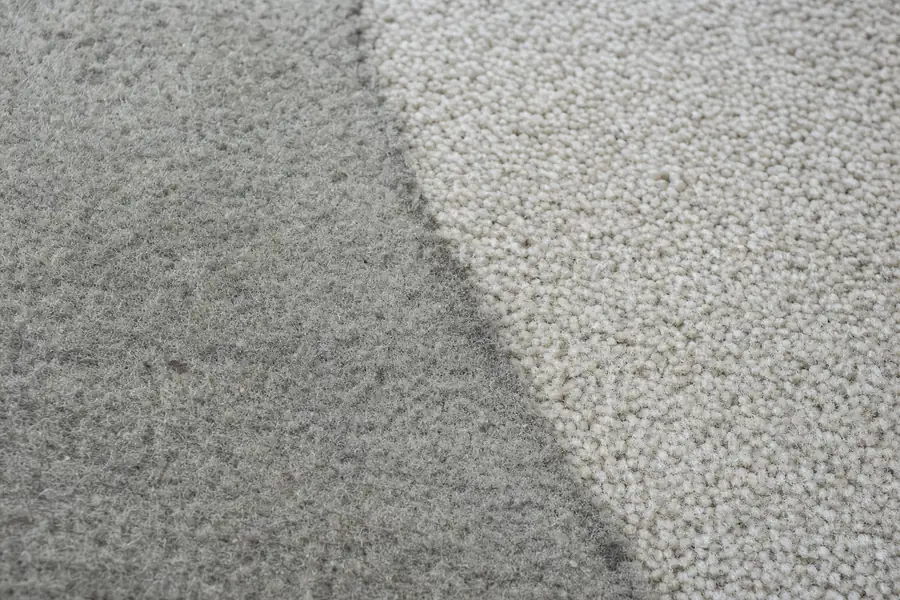 Of matted, gray high-traffic carpet fibers beside a cleaner section of carpet