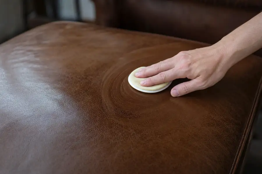 Applying leather conditioner to a couch cushion with a small pad in circular motions