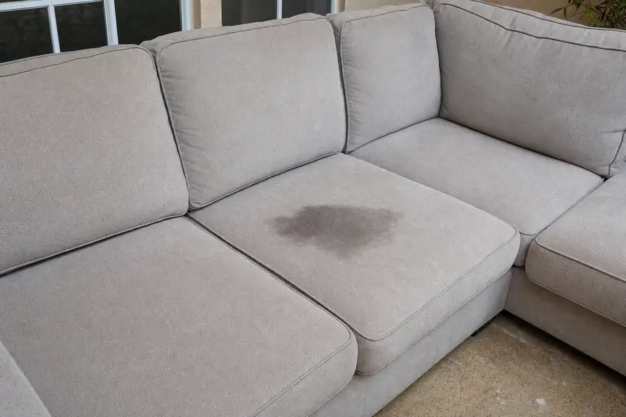 Light gray microfiber sectional with a visible dark stain on one seat cushion