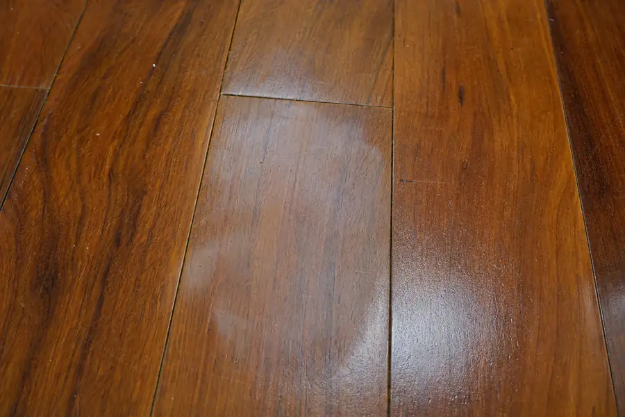 Of a dull cloudy patch on hardwood boards next to shinier planks